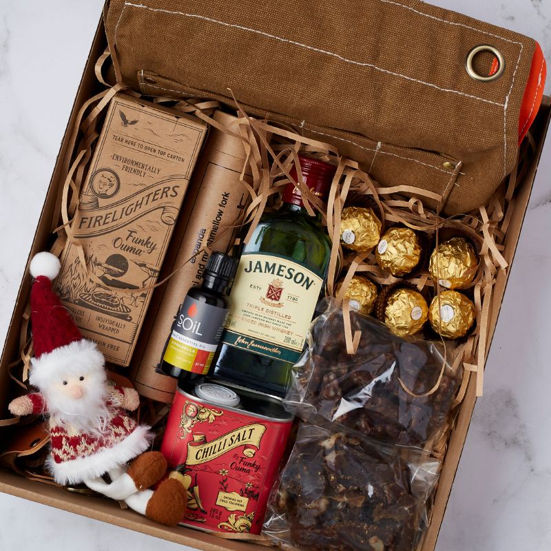 Home for the Holidays Gift Box featuring Jameson whiskey, Ferrero Rocher chocolates, biltong, firelighters, gourmet salt, and more festive treats.