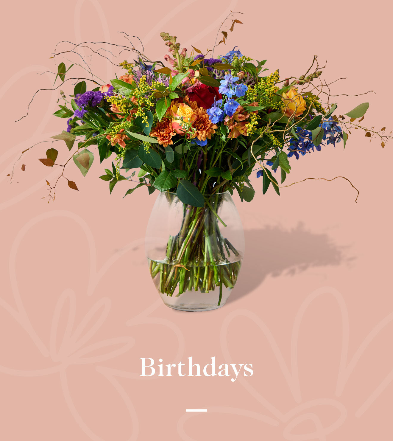 Vibrant bouquet of mixed flowers in a clear glass vase against a soft pink background. Fabulous Flowers and Gifts. Birthdays.