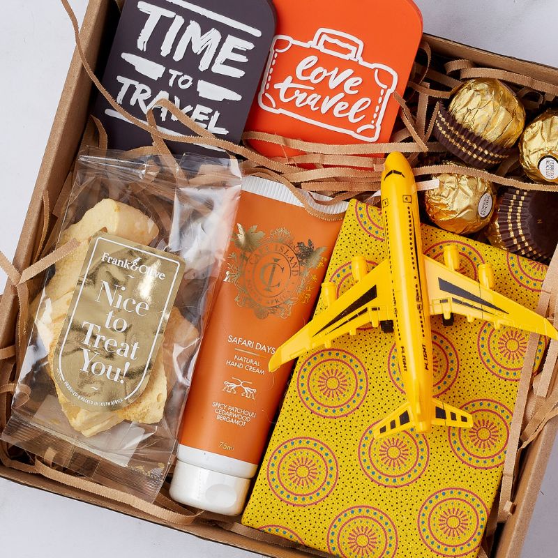 Top-down view of a travel gift set featuring Safari Days hand cream, airplane toy, snacks, and travel-themed accessories.