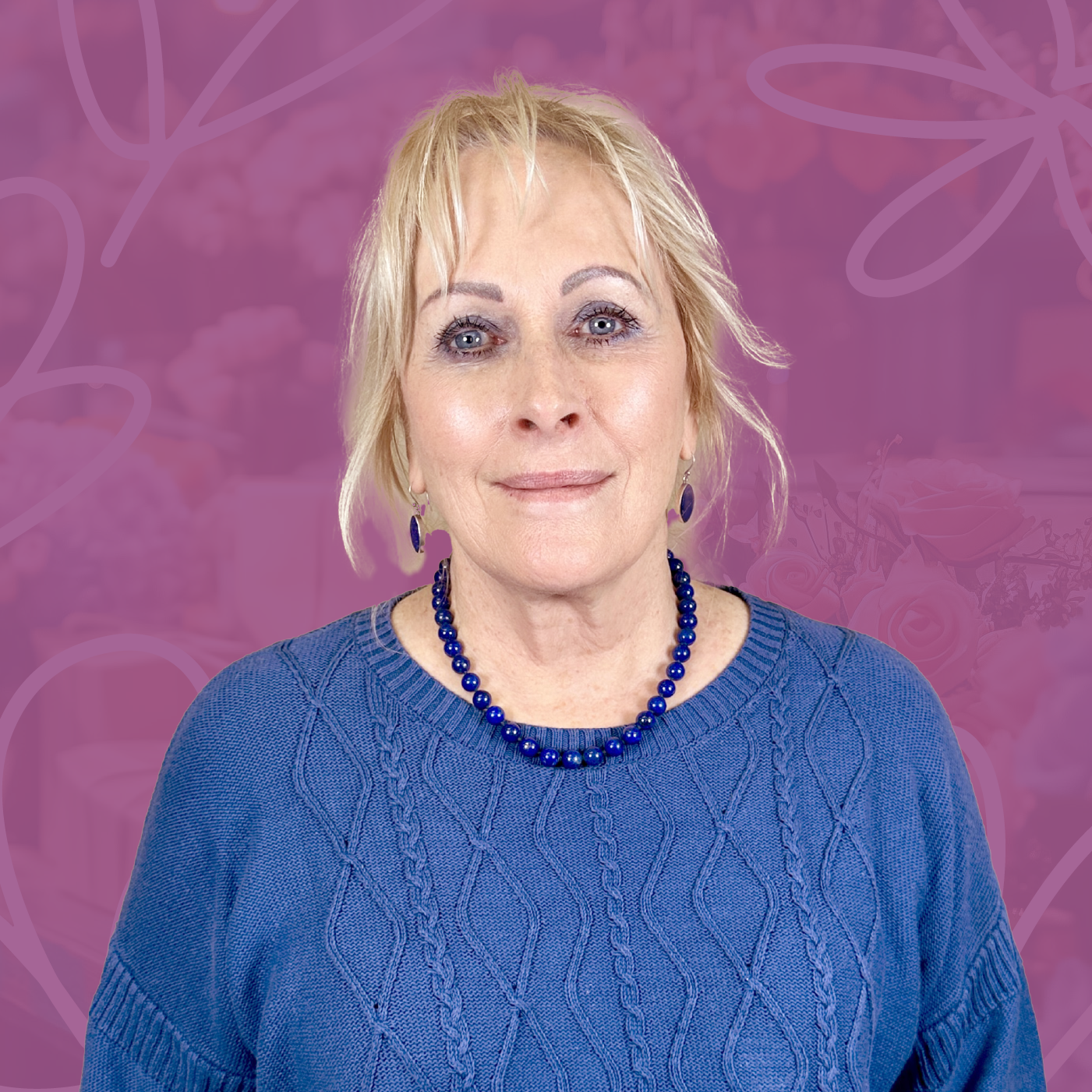Portrait of Josie van Aswegen, team member at Fabulous Flowers, smiling in a blue sweater with a beaded necklace against a purple background with floral designs. MEET THE TEAM at Fabulous Flowers and Gifts. Connect with Josie for expert floral and gift advice.