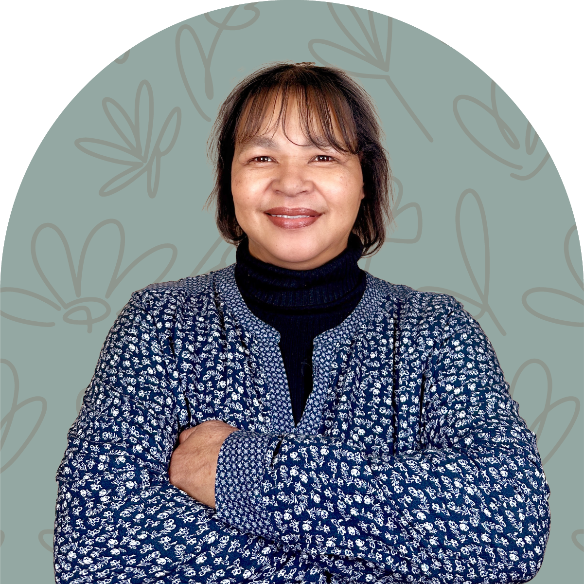 Portrait of Lillian, a team member at Fabulous Flowers, smiling in a patterned blue sweater against a green background. MEET THE TEAM at Fabulous Flowers and Gifts.