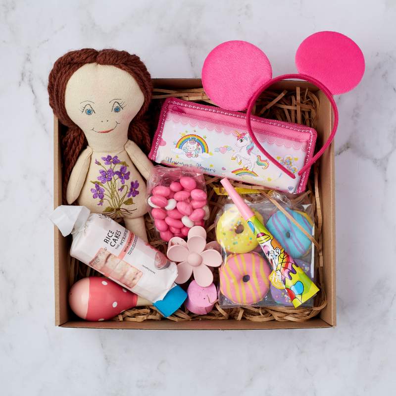 Little Princess Gift Box featuring a handmade doll, pink headband, unicorn pencil case, rice cakes, party blower, and colourful treats.