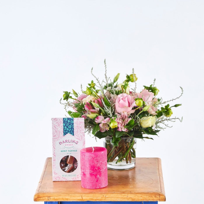 Love and Light Flower Gift Set featuring a vibrant arrangement of pink roses and mixed blooms with a pink candle and mint toffee in a stylish display.