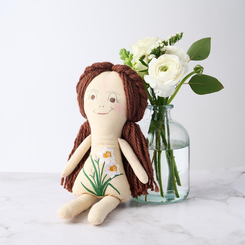 New Beginnings Gift Set featuring a handcrafted doll with embroidered white flowers, paired with a vase of fresh white blooms.