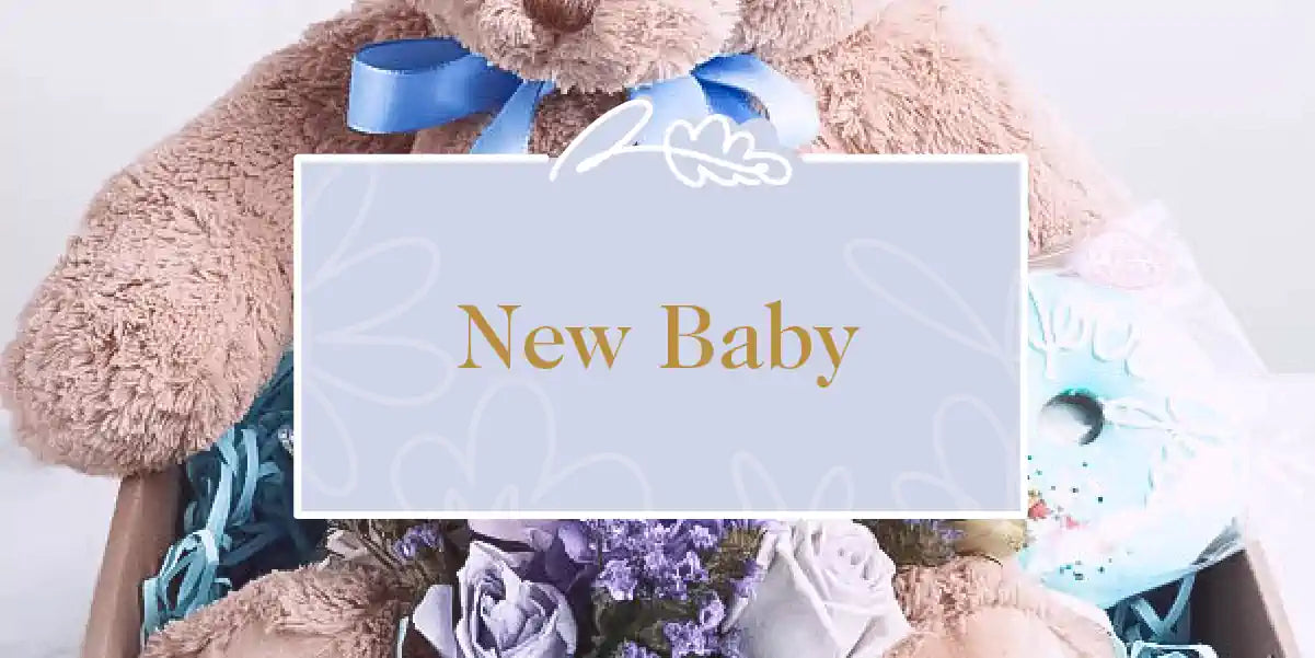 A charming teddy bear surrounded by a delightful selection of gifts and flowers for a new baby. Fabulous Flowers and Gifts - New Baby