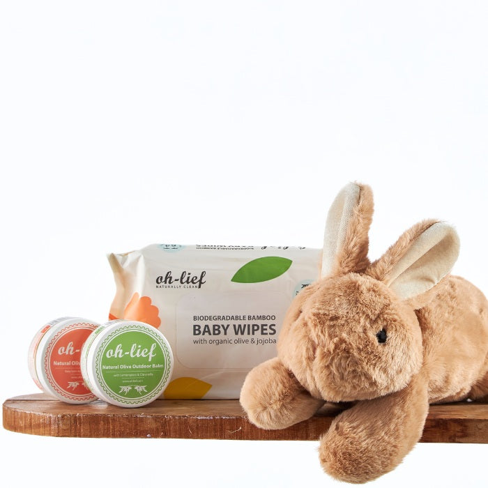 Eco-friendly Organic Hopper Baby Essentials with a soft brown bunny plush, organic baby wipes, and natural balms displayed on a rustic wooden shelf for newborn care.