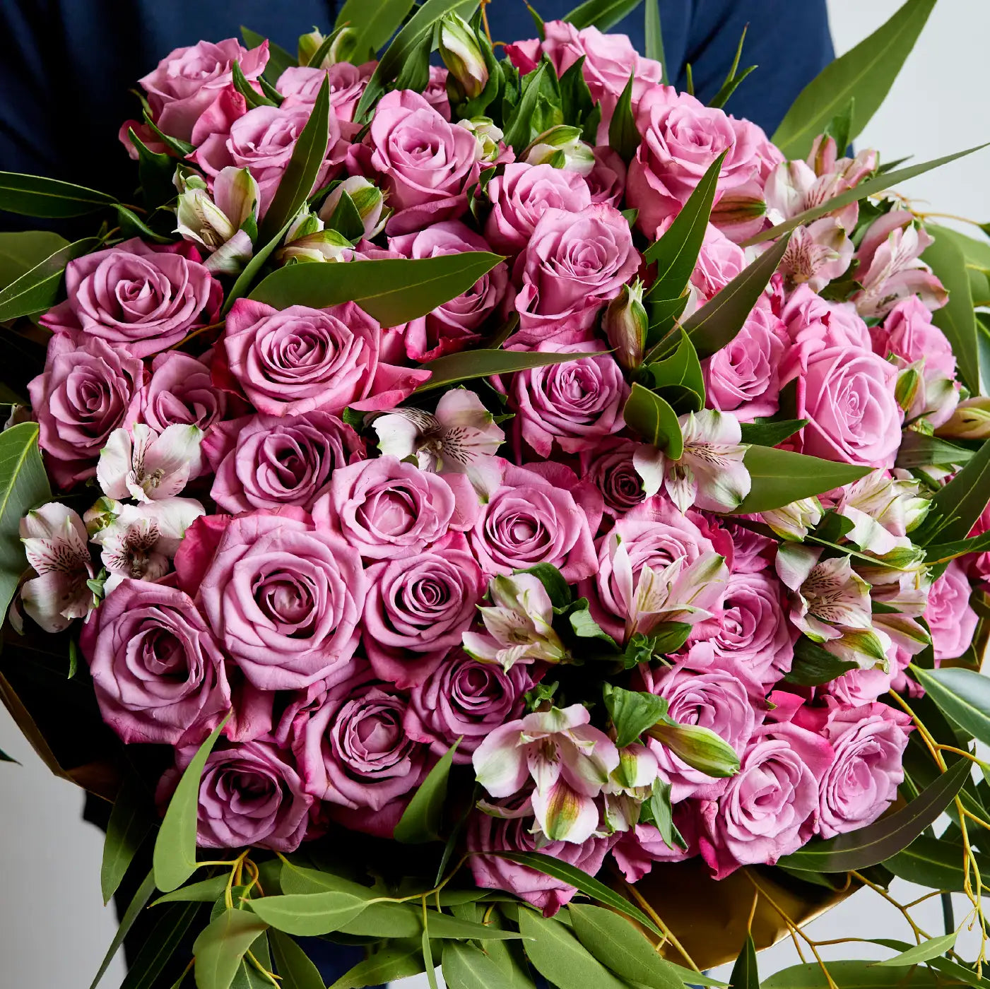 Close-up of a bouquet of pink and purple roses with greenery, highlighting Sustainable Practices. Text explains eco-friendly practices such as water recycling and organic pest control. Our Difference. Fabulous Flowers and Gifts.