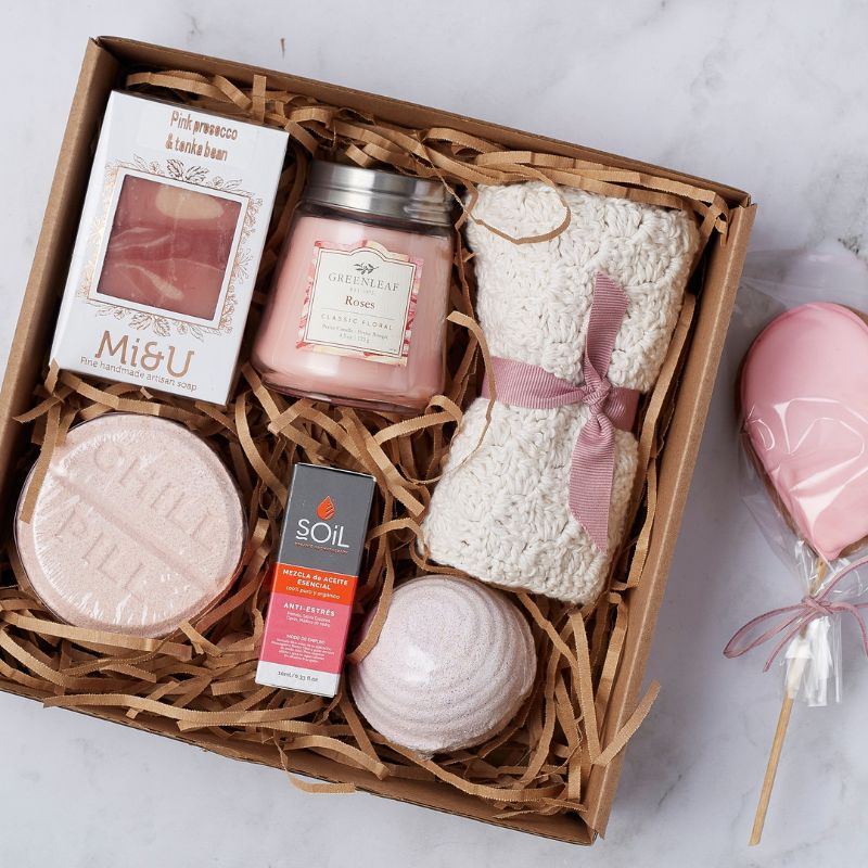 Luxurious self-care gift box featuring rose candle, bath towel, essential oils, and a heart-shaped cookie for relaxation.