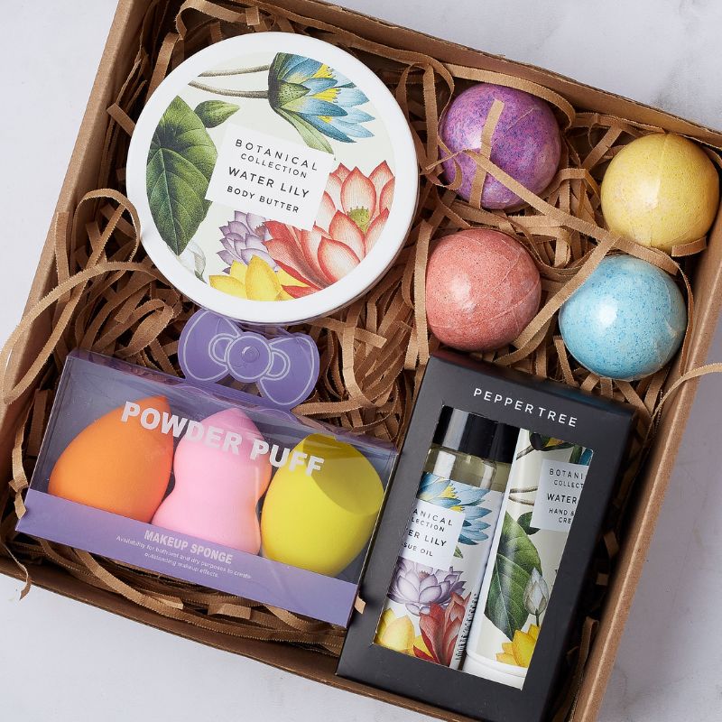 Close-up of gift box with Water Lily body butter, makeup sponges, botanical hand cream, bath bombs, and essential oil.