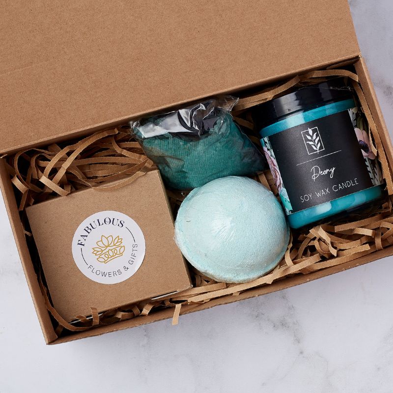 Close-up of a gift box with a Fabulous Flowers box, teal bath bomb, soy wax candle, and bath salts.