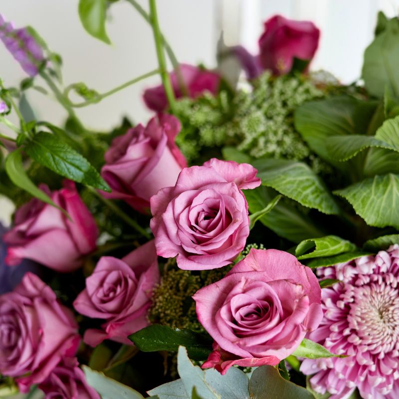 Close-up of soft pink roses surrounded by lush greenery in a delicate floral display.