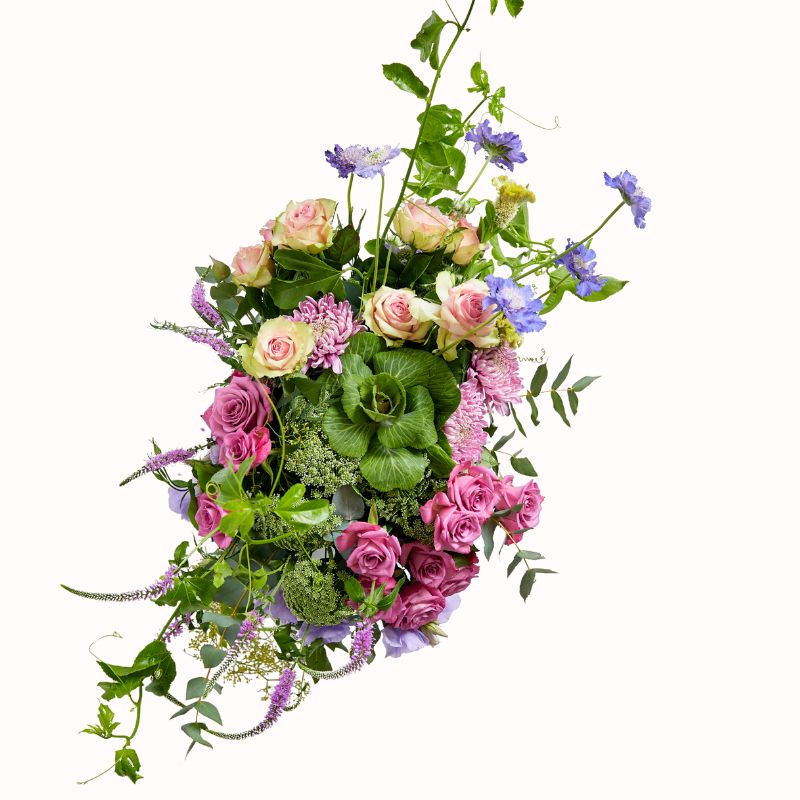 Overhead view of a pastel flower arrangement with roses, peonies, and cascading foliage.