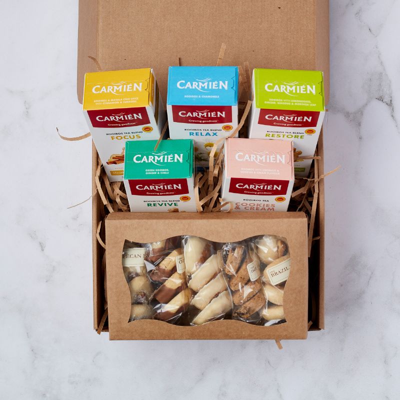 Opened Regal TeaTime Delights Hamper showing six colourful Carmién rooibos tea boxes and nut-based treats in a kraft box.