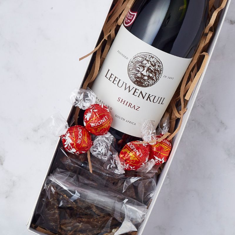 Close-up of Leeuwenkuil Shiraz wine gift box with Lindt truffles and dried meat snacks.