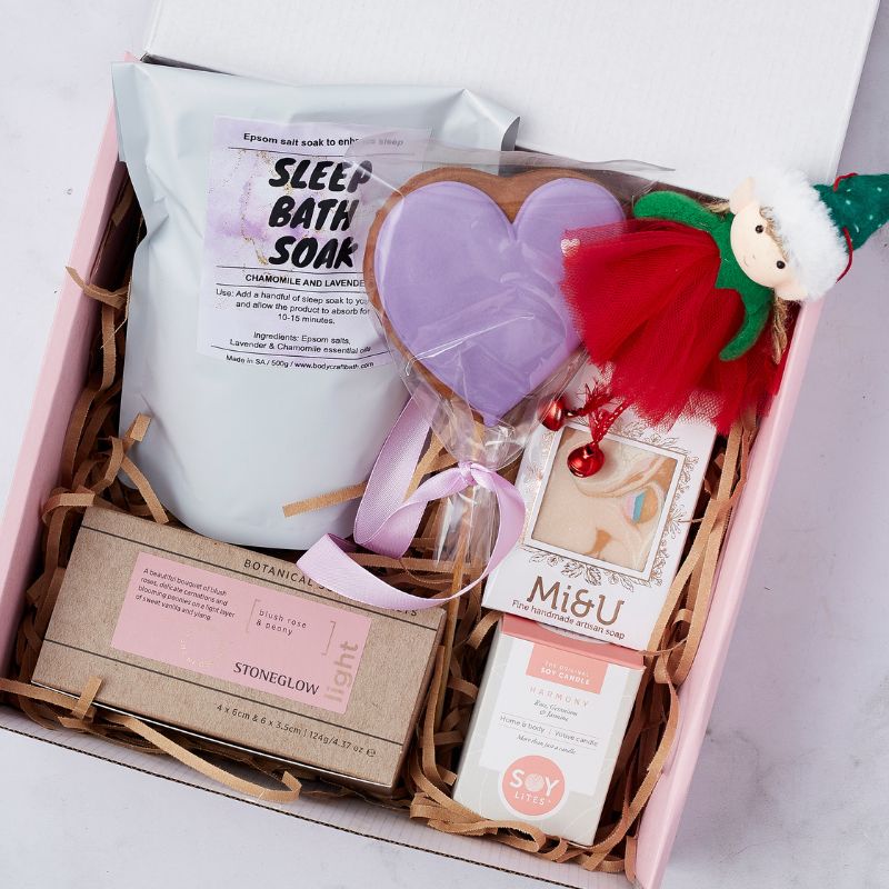 Snowfall Spa Gift Set featuring chamomile and lavender bath soak, heart-shaped bath bomb, artisan soap, soy candle, and holiday elf plush.