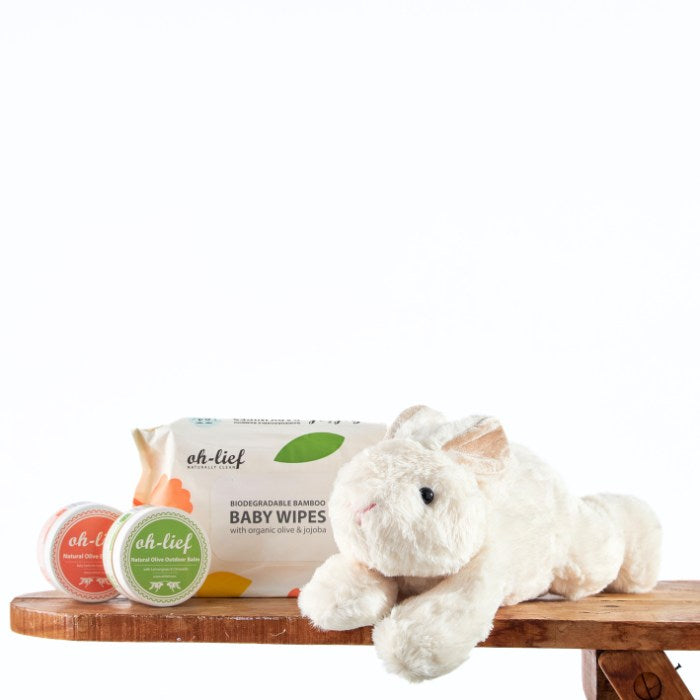 Snuggle Bunny Baby Bundle featuring a plush white bunny, biodegradable bamboo baby wipes, and natural skin balms on a wooden surface, perfect for gentle baby care.