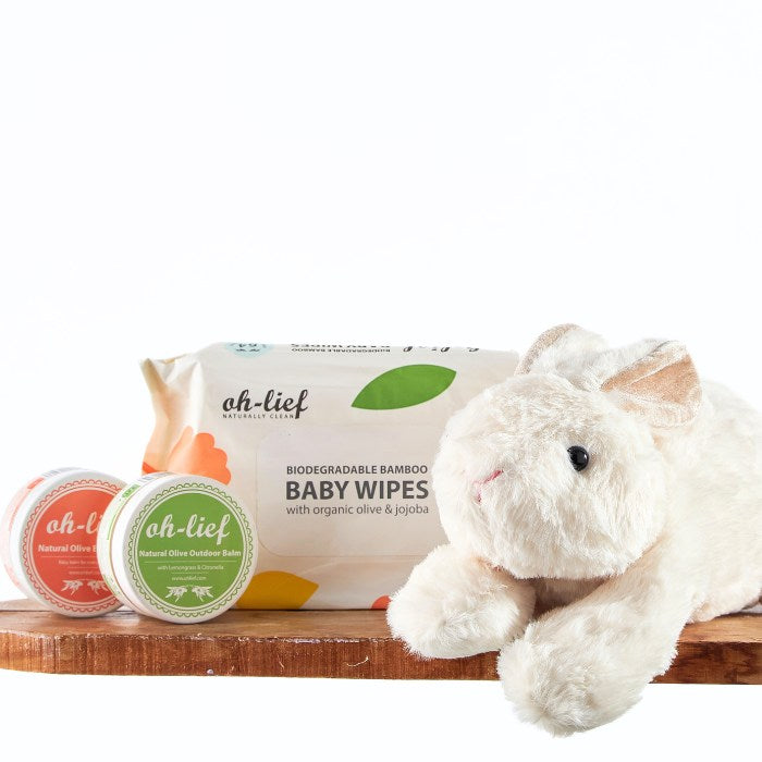 Adorable white plush bunny alongside biodegradable bamboo baby wipes and organic balms from the Snuggle Bunny Baby Bundle, displayed on a rustic wooden shelf.