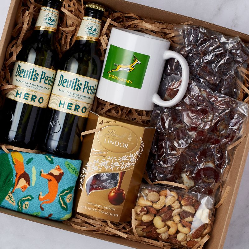 South African-themed gift box including Springboks merchandise, Devil's Peak Hero beers, biltong, Lindt chocolates, and assorted snacks.