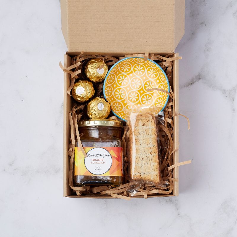 Gift box with Ferrero Rocher chocolates, Leo's Little Jars orange & cardamom jam, hand-painted yellow ceramic bowl, and Italian biscotti