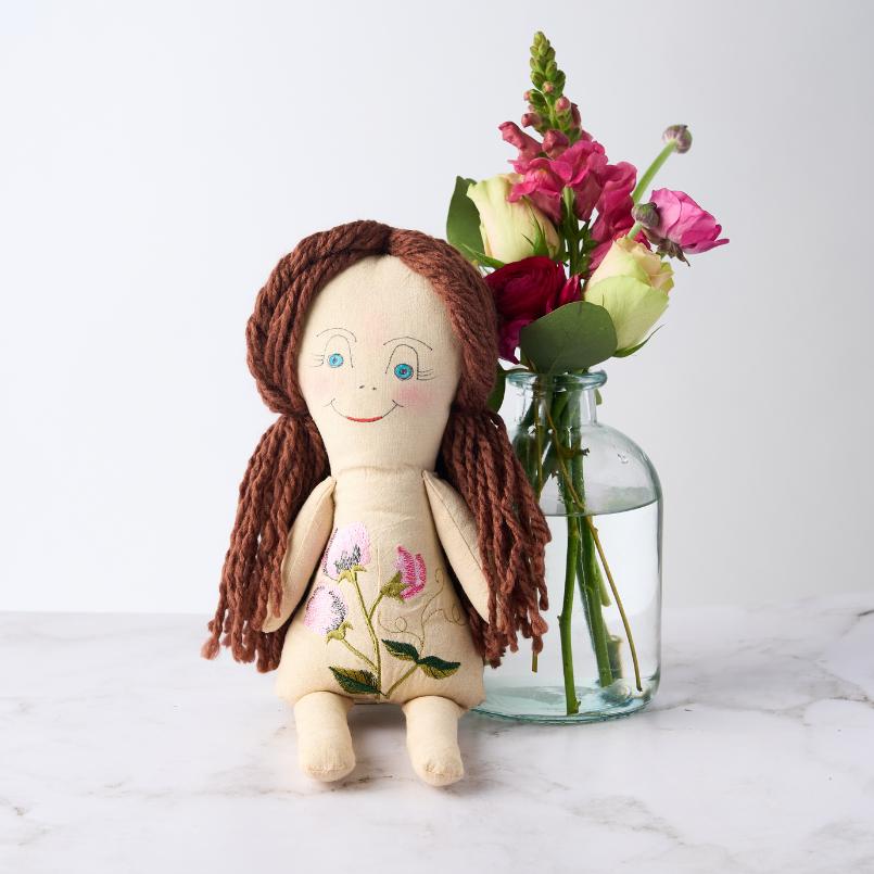 Handmade Sweet Pea Elegance Doll displayed next to a vase of vibrant pink and white flowers.