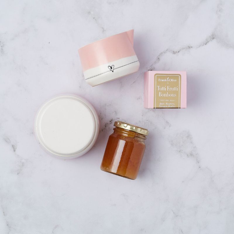 Gift set with ceramic pink heart cup, tutti frutti bonbons, and a mini jar of honey.