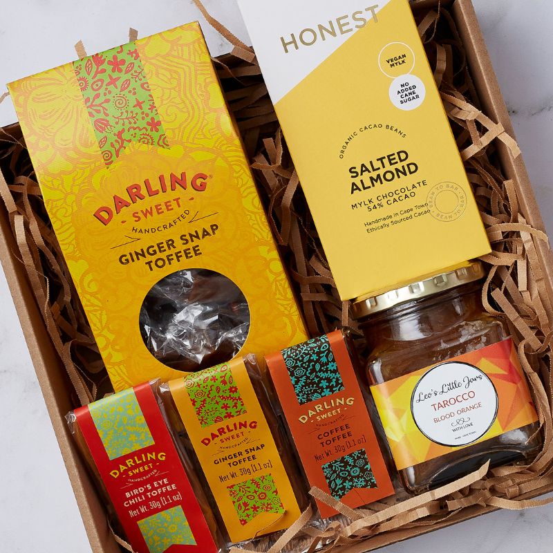 Close-up of a gourmet gift hamper with Darling Sweet toffees, Honest chocolate, and Lee’s Little Jars blood orange preserve