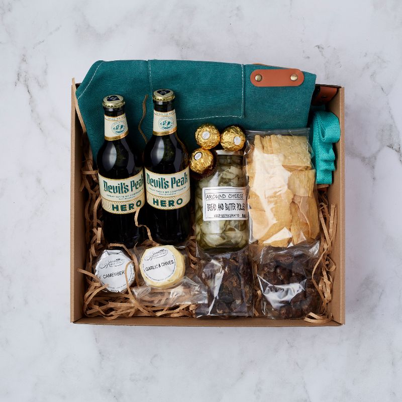 Tasting Adventure Gift Box with Devil's Peak Hero non-alcoholic lagers, Ferrero Rocher chocolates, bread and butter pickles, artisanal cheeses, crackers, biltong bites, and a reusable canvas cooler bag.