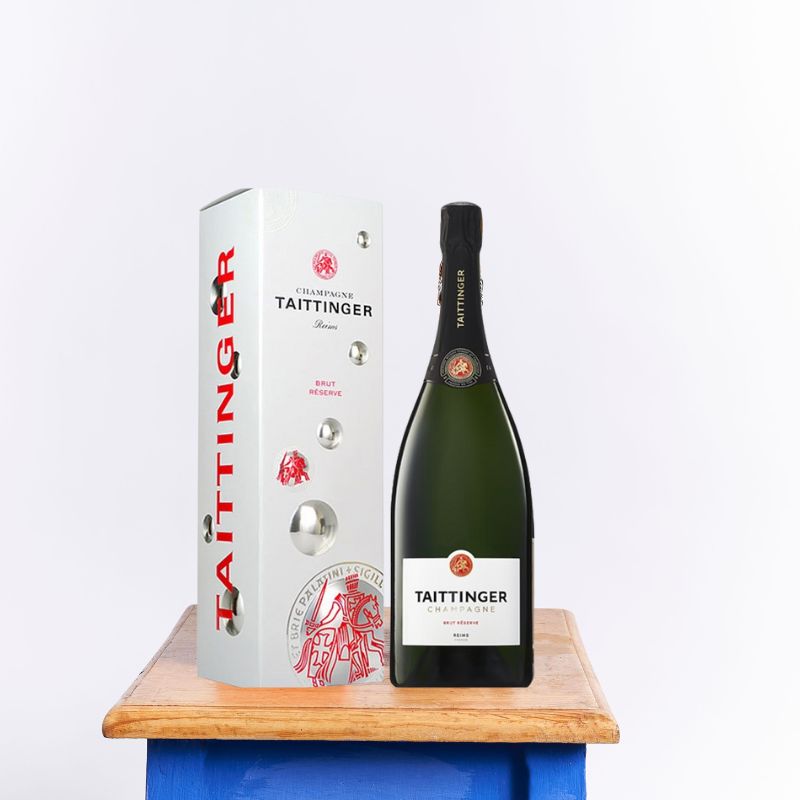 Taittinger Brut Reserve champagne bottle with a sleek white and red gift box, elegantly displayed on a wooden table.