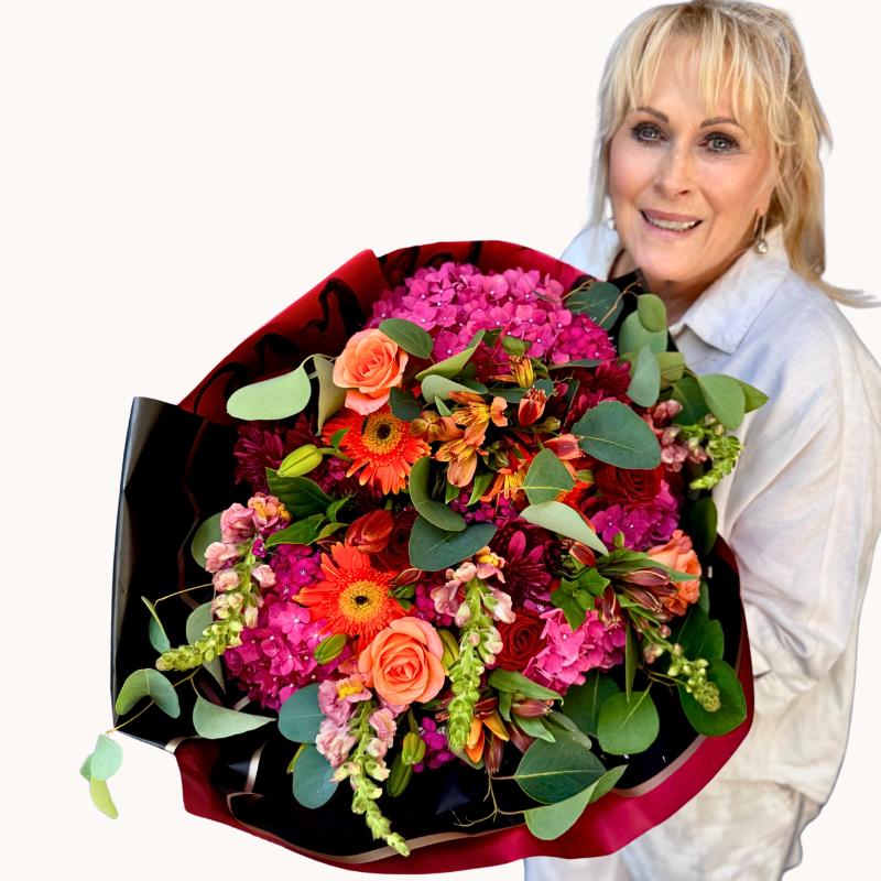 Vibrant Storyteller's Garden bouquet featuring hydrangeas, gerberas, snapdragons, and roses, held by a smiling person - Fabulous Flowers & Gifts."