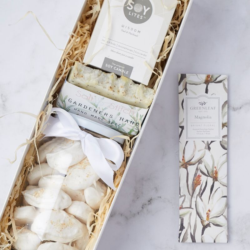 Luxury gift set featuring a soy candle, handmade soap, floral sachet, and ribbon-wrapped meringues in elegant packaging.