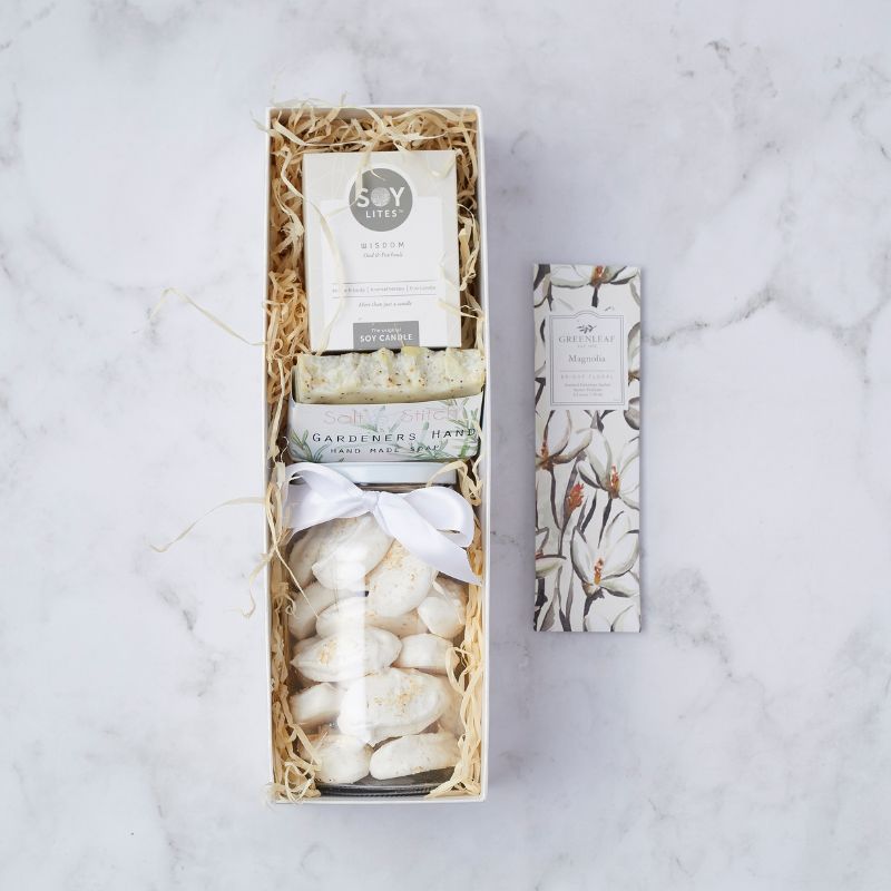 Gift box with soy candle, gardener’s hand soap, magnolia-scented sachet, and white meringues tied with a ribbon.