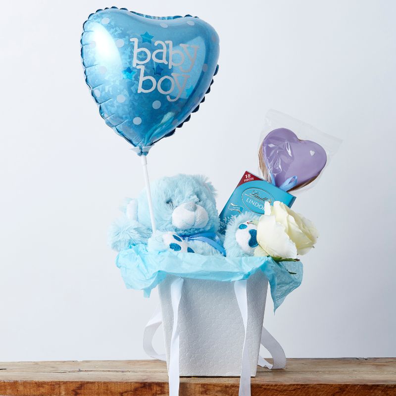 Welcome Home Baby Boy gift box with blue teddy bear, heart-shaped 'Baby Boy' balloon, Lindt chocolates, and white rose