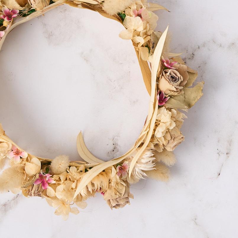 Close-up of beige dried flower crown featuring soft blooms and subtle pink highlights.