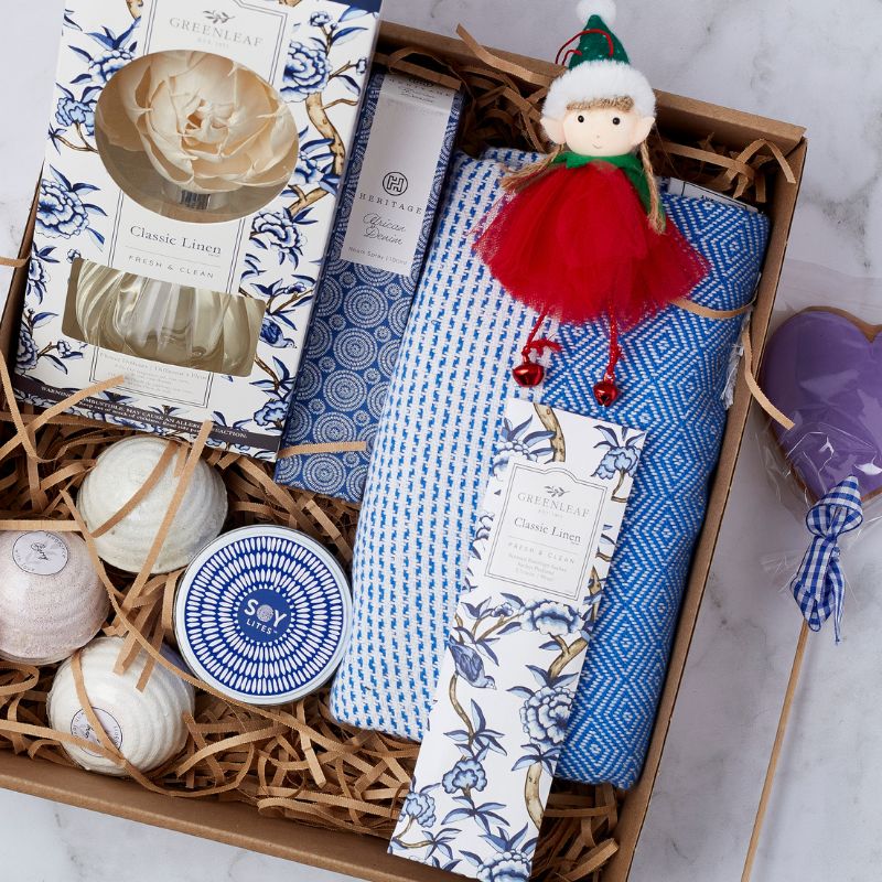 Winter Wonderland Spa Gift Box featuring a classic linen reed diffuser, hand cream, soy candle, festive bath bombs, hand towel, and holiday elf plush.