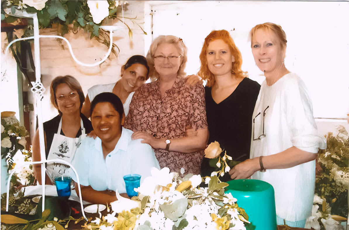 osie van Aswegen with her team at Fabulous Flowers and Gifts, smiling together amidst a workspace filled with floral arrangements.