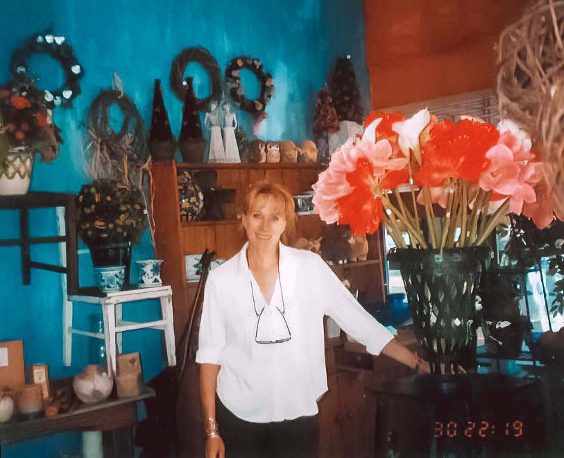 Josie van Aswegen, founder of Fabulous Flowers and Gifts, stands in her beautifully decorated floral shop, showcasing vibrant amaryllis blooms.