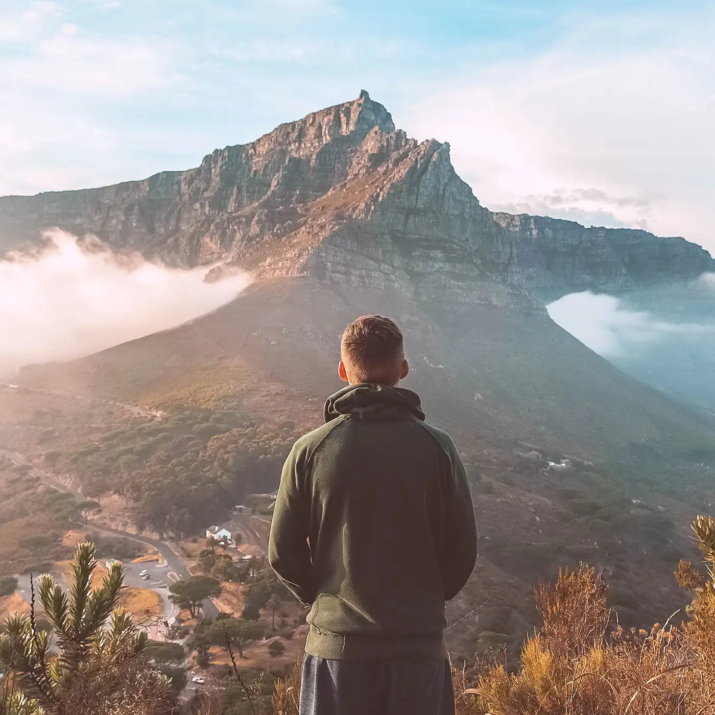 Man standing on a hilltop overlooking a misty mountain landscape. Fabulous Flowers and Gifts. Cape Town.