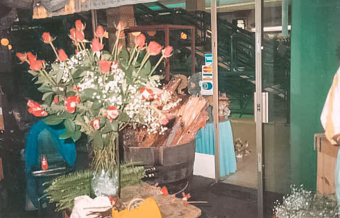 A bouquet of red roses in a vase inside Josie van Aswegen's old shop at Fabulous Flowers and Gifts, showcasing rustic floral arrangements and wooden decor.