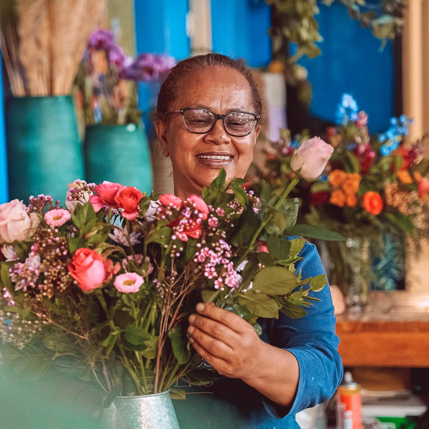 Florist smiling while arranging a vibrant bouquet, emphasising the diverse range of flowers and gifts for all occasions by Fabulous Flowers and Gifts.