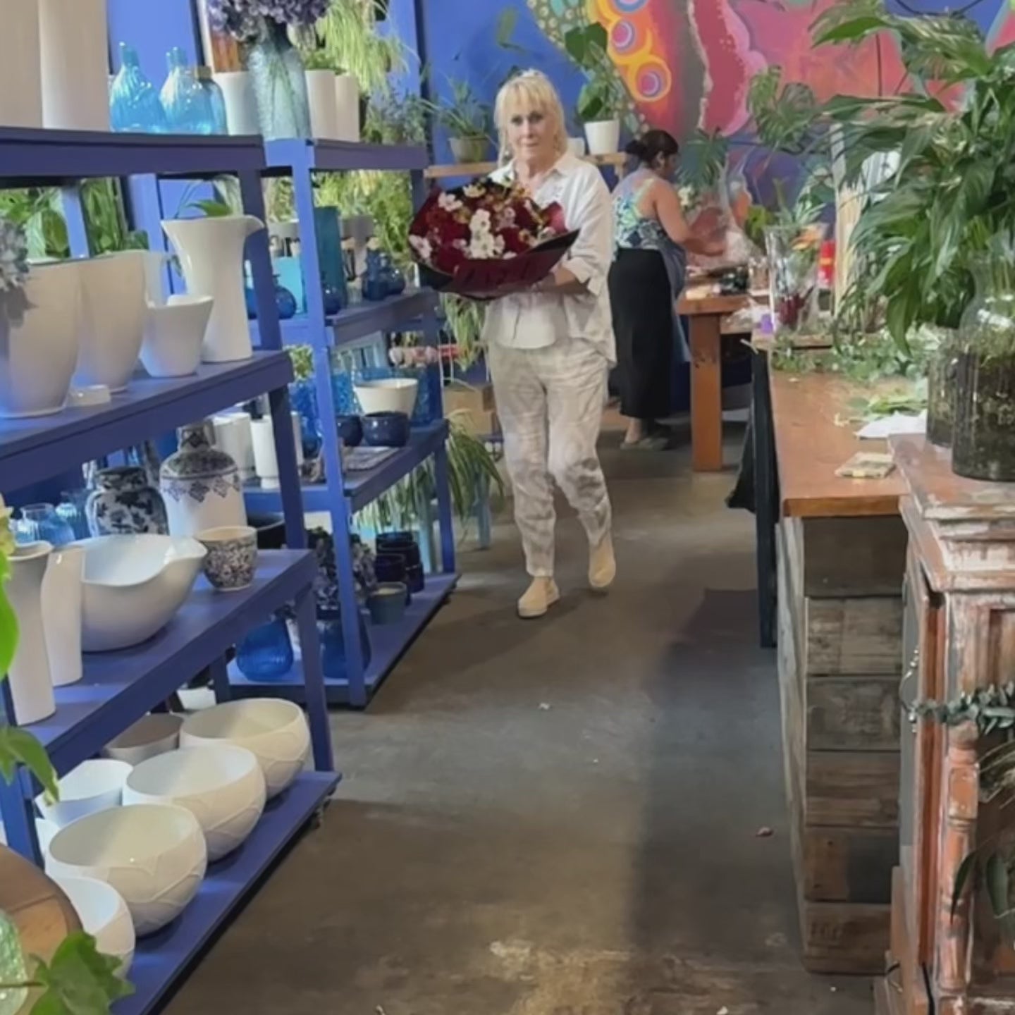 Video showcasing the Wild Abundance bouquet, highlighting white cosmos, yellow daisies, red roses, and vibrant foliage in close-up views.